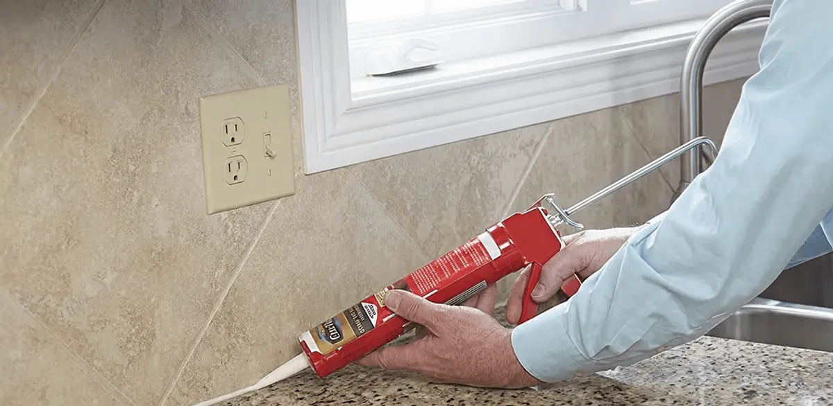 Handyman applying caulk along a kitchen backsplash and countertop seam in Charleston, SC