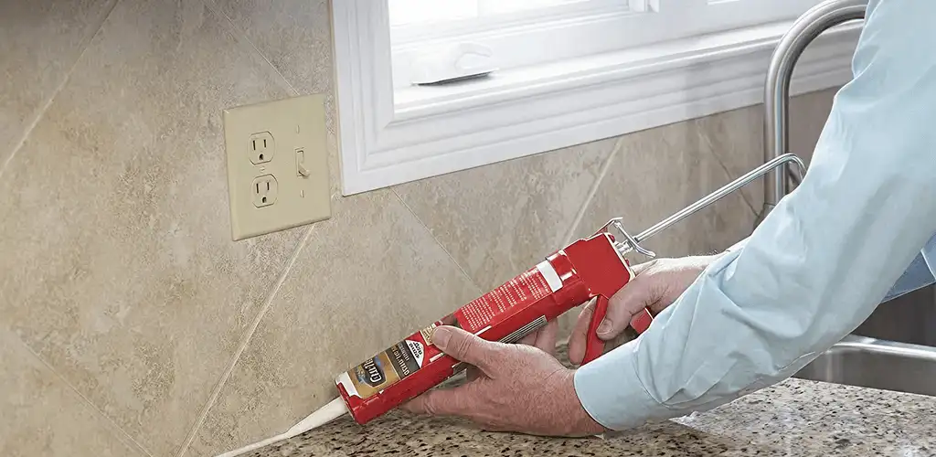 Handyman applying caulk along a kitchen backsplash and countertop seam in Charleston, SC