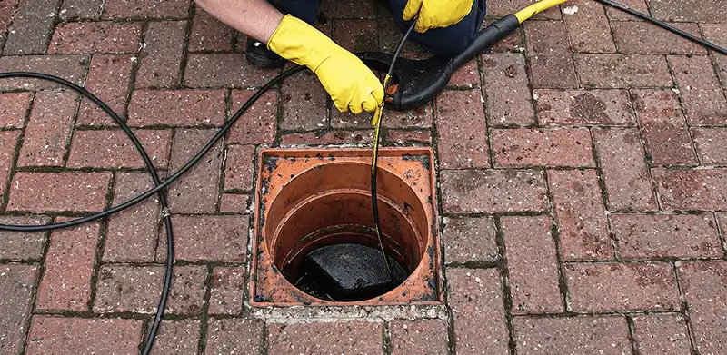 Drain cleaning technician using a drain snake to clear a clogged drain in Charleston, SC