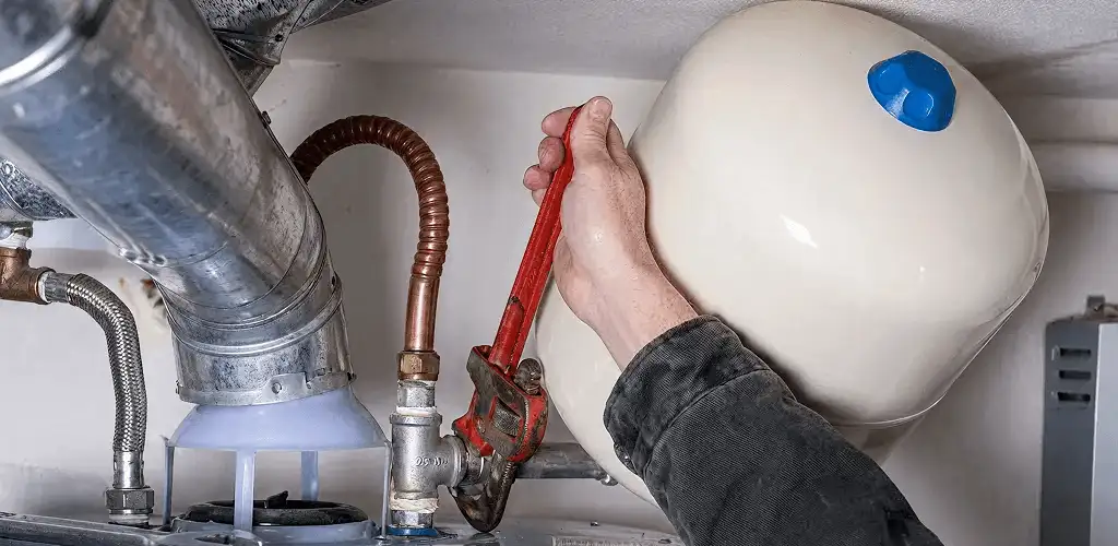 Water heater repair technician tightening plumbing connections near a tank unit in Charleston, SC